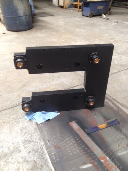 Soporte industrial de acero maquinado con bujes de bronce para sistemas mecánicos.